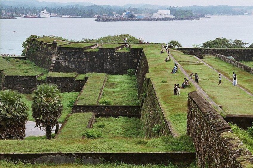 A historical fort with grassy areas and a body of water in the background. 2