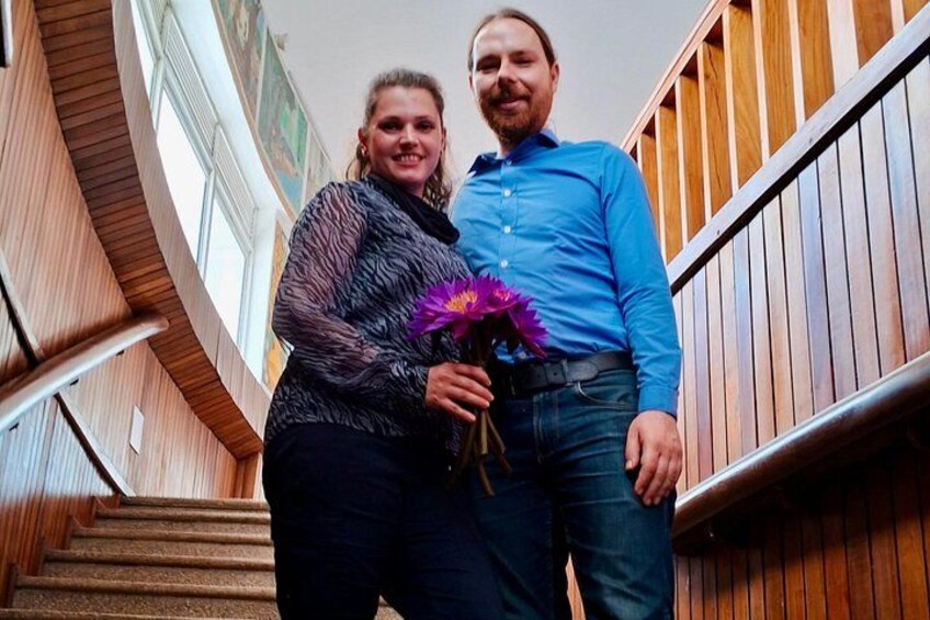 A man and a woman standing on a wooden staircase with a railing. 3