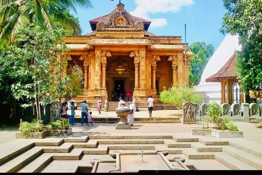 A temple with a central entrance, steps leading up to it, and people around. 2