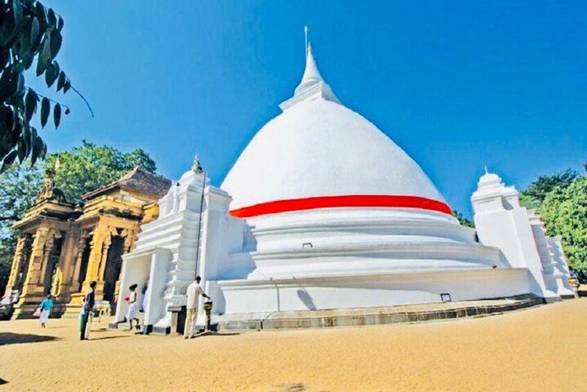 A white stupa with a red stripe, surrounded by traditional architecture. 3