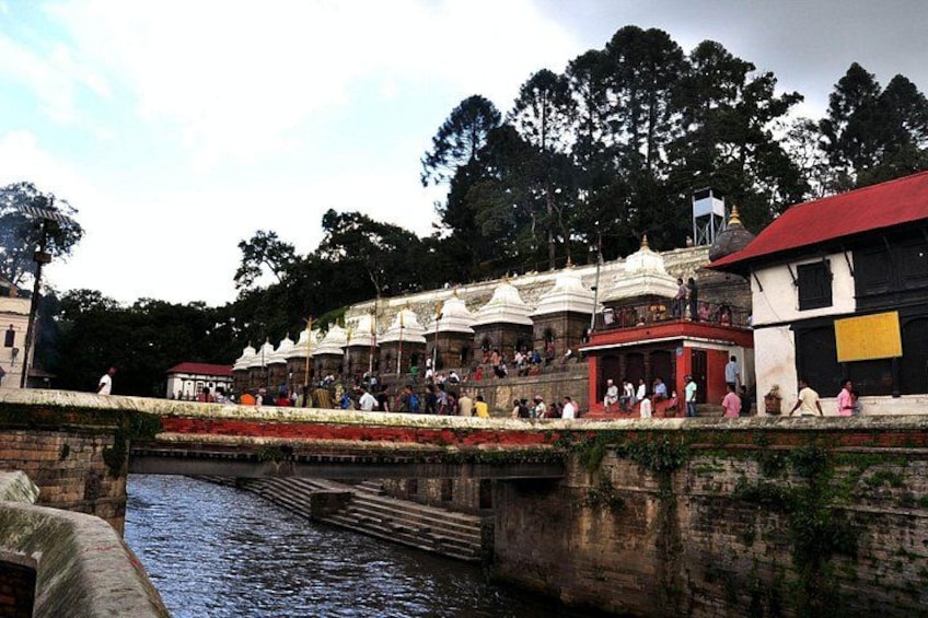 Una passeggiata lungo il fiume con persone, edifici a cupola bianca e un ponte. 2