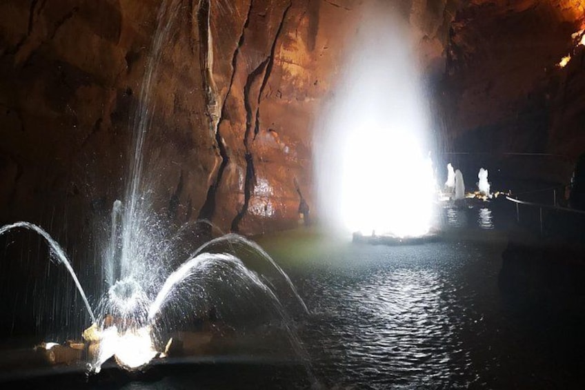 Eine Höhle mit einem Wasserbrunnen, steinernen Wänden und einer hellen Lichtquelle. 2