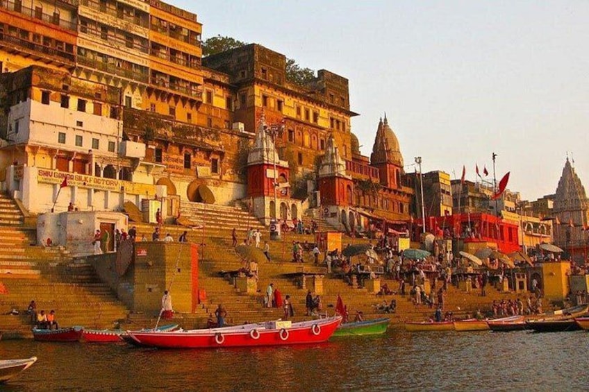 A riverside scene with boats, steps leading to a temple, and people. 1