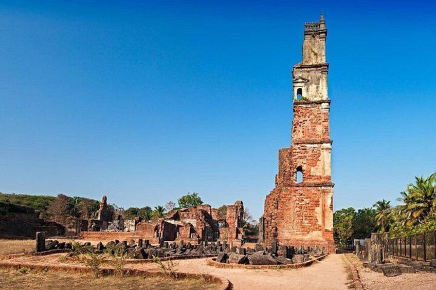 Ein historischer Ort mit einem markanten Backsteinturm, Ruinen und einem strahlend blauen Himmel. 4