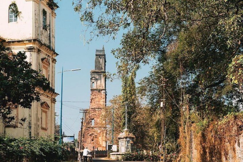 Ein historisches Gebäude mit einem Glockenturm, umgeben von Bäumen und einer Straßenlaterne. 2