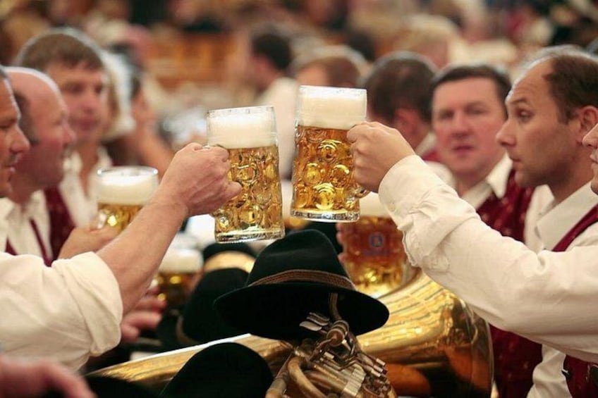 A group of people toasting with large beer mugs, wearing traditional attire. 2