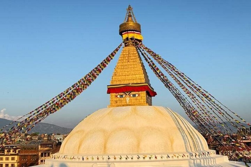 A large white stupa with a golden spire, surrounded by colorful prayer flags. 1