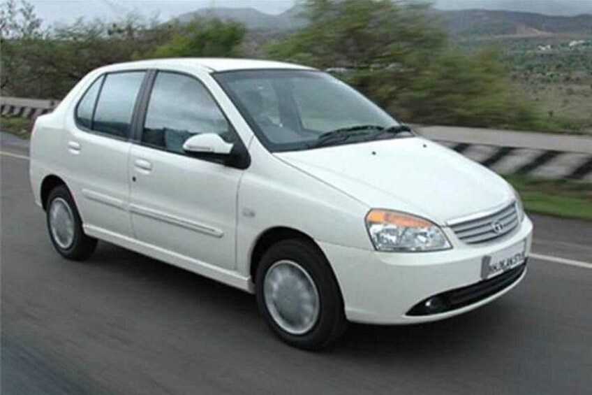 A white sedan driving on a highway with a mountainous landscape in the background. 2