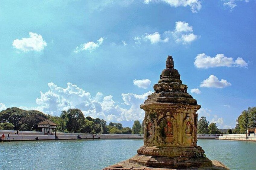 A historical stone structure by a calm body of water with a clear sky. 4