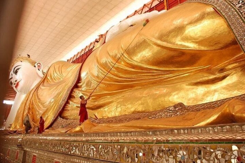 A large golden statue of a reclining figure with attendants. 3
