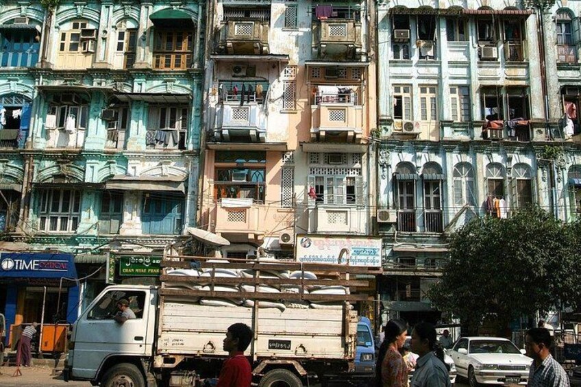 A busy street with multi-story buildings, a white truck, and pedestrians. 4