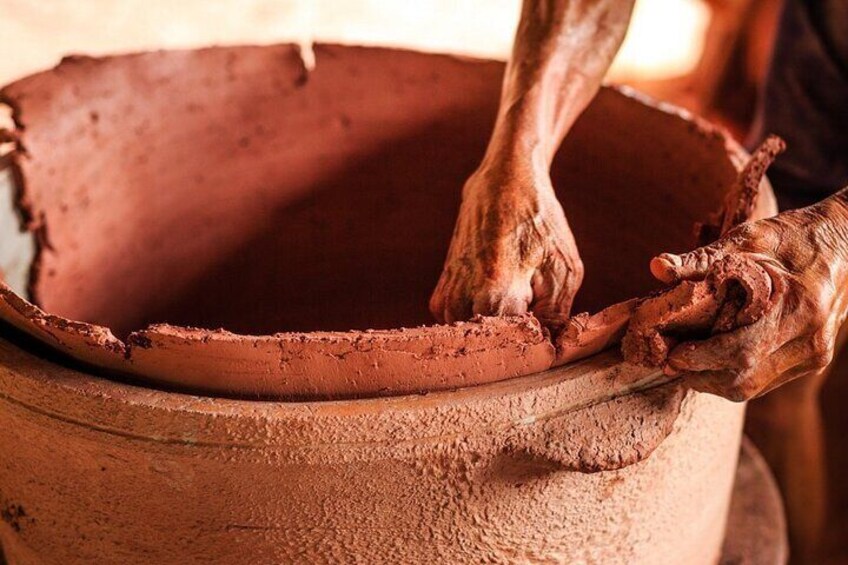 Hands shaping clay in a pot. 4