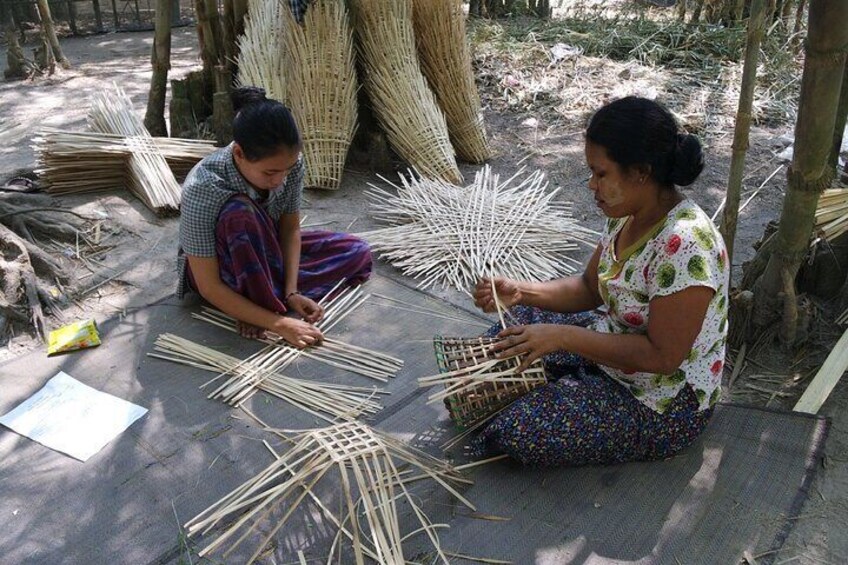 Two women sitting on the ground, working with bamboo sticks. 5