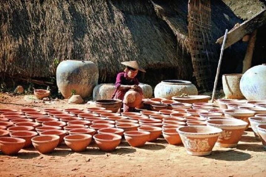 A person working with clay pots in a rural setting. 1