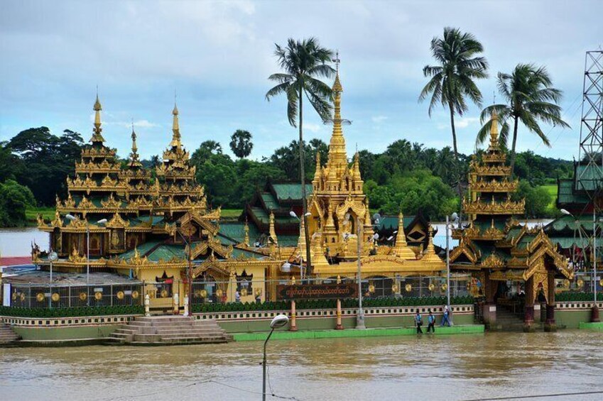 A golden temple complex with multiple pagodas, surrounded by palm trees and a river. 4