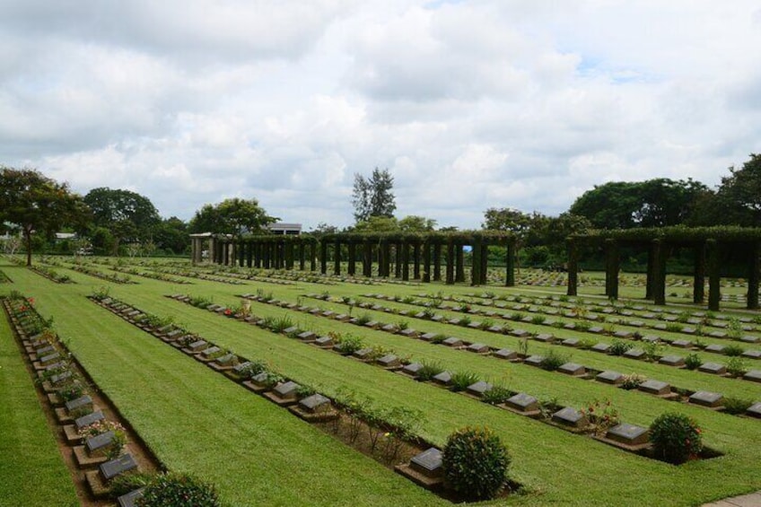 A cemetery with rows of graves, greenery, and trees. 4