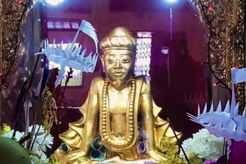 A golden statue of a seated figure with a meditative posture, surrounded by decorative elements and flowers. 2