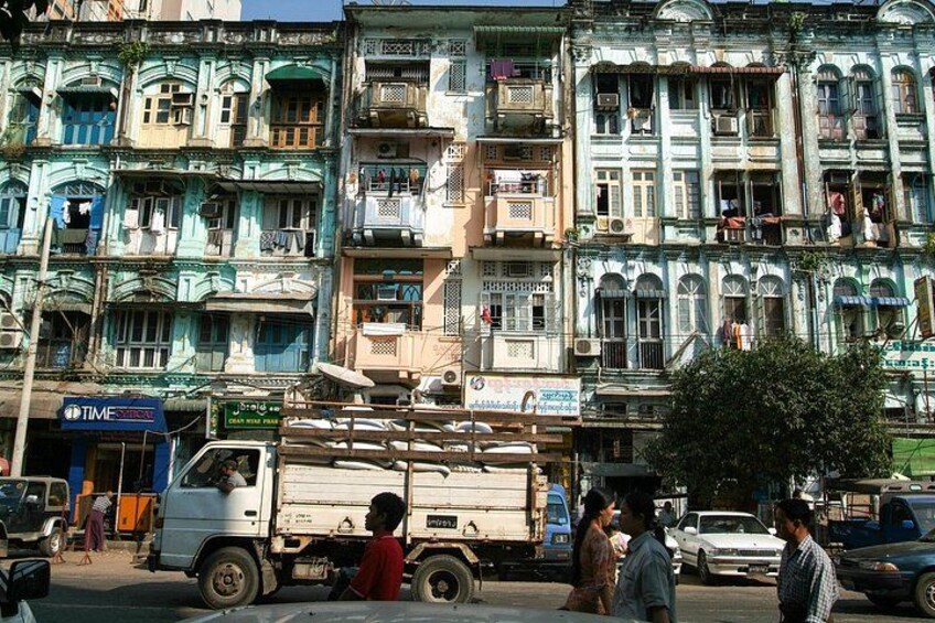 A busy street with multi-story buildings, a truck, and pedestrians. 5