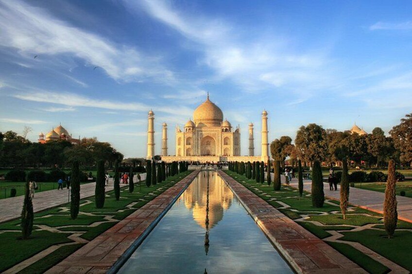 The Taj Mahal with a reflection in the water, surrounded by a symmetrical garden and minarets. 2