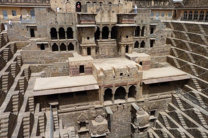 An ancient, multi-tiered stone structure with arched walkways and a central elevated platform. 2