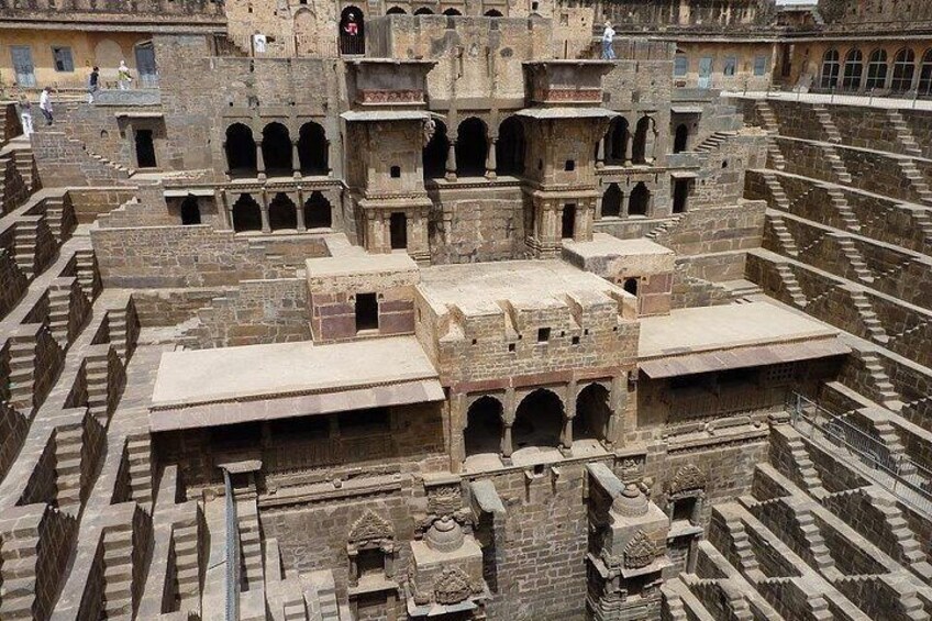 An ancient architectural complex with multiple levels, arched doorways, and intricate stonework. 2