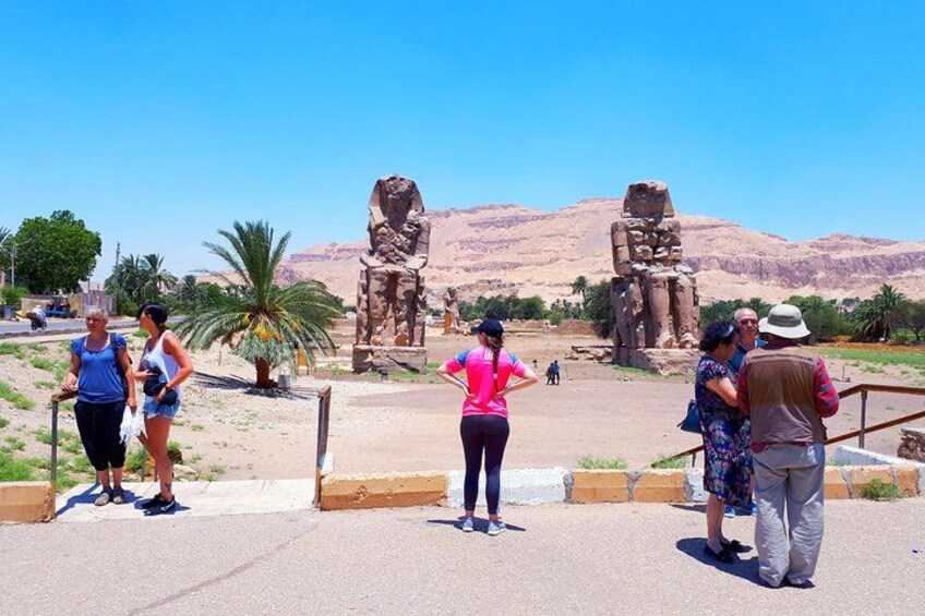 Turistas observando antiguas estatuas egipcias en un paisaje desértico. 2