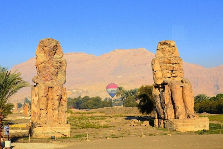 Deux grandes statues de pierre, un ciel dégagé et un ballon à air chaud en arrière-plan. 5