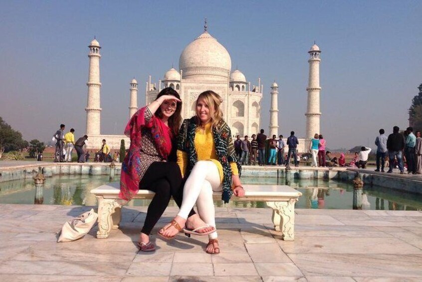 Two people sitting on a bench in front of the Taj Mahal. 3
