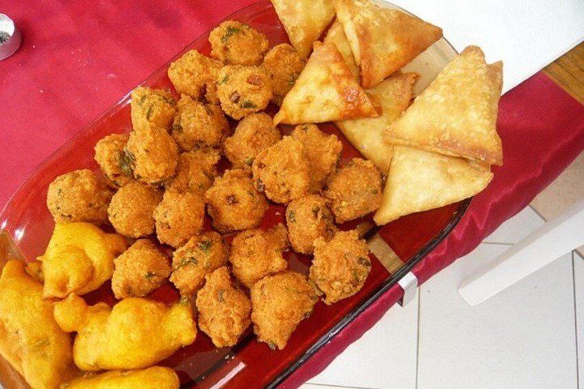 A tray of fried snacks including samosas and fritters. 4