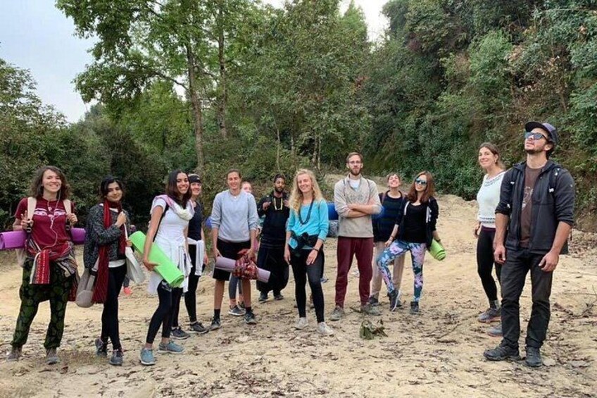A group of people standing on a sandy area with trees in the background. 1