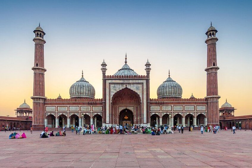 A large mosque with multiple domes and minarets, a spacious courtyard, and people gathered around. 3