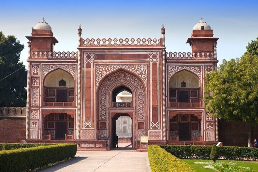 A large, ornate red and white marble gateway with intricate designs and two domed towers. 2