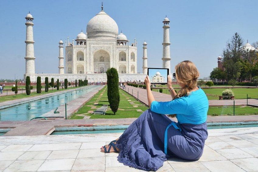 En person sidder på jorden og tager et billede af Taj Mahal med en tablet. 5