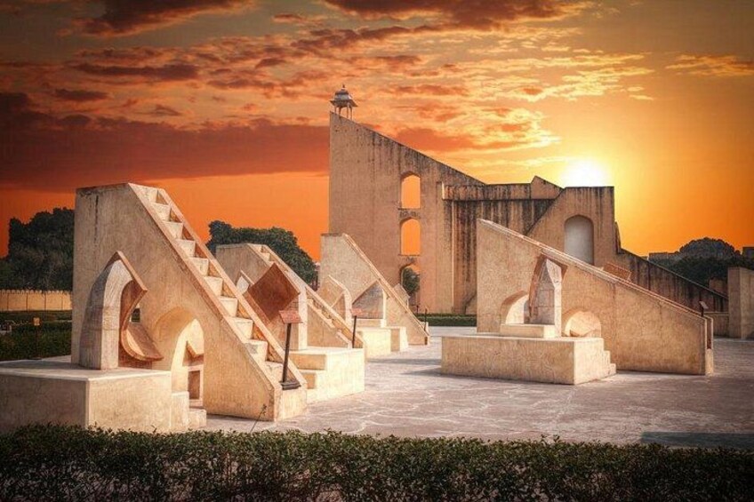 Un bâtiment historique doté d’escaliers en arc de cercle et d’une tour, se dressant sur fond de ciel au coucher du soleil. 2