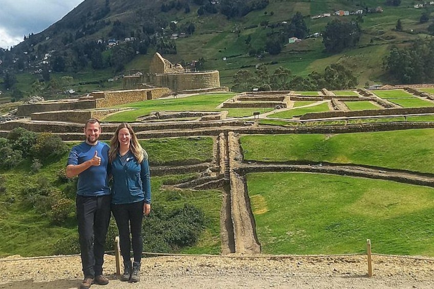 Una pareja frente a un sitio histórico con campos en terrazas y ruinas antiguas. 1