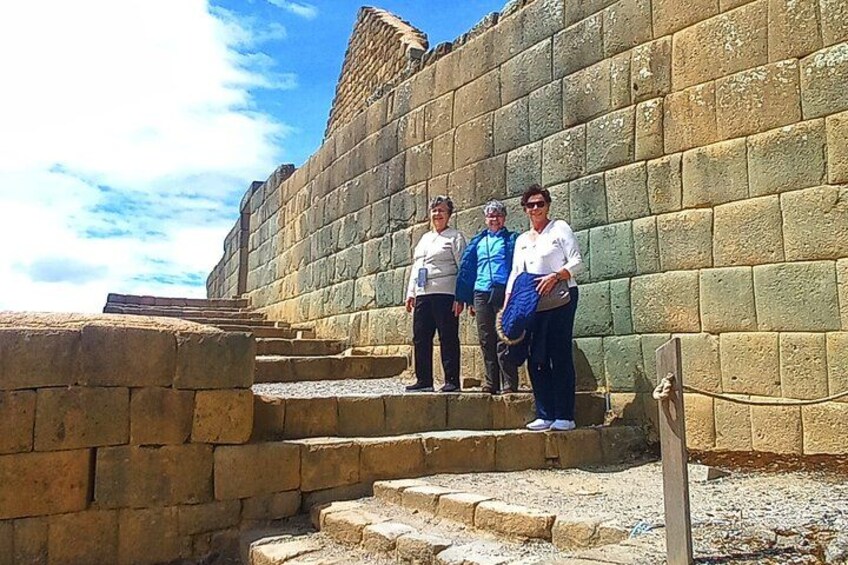 Un grupo de personas de pie sobre escalones de piedra frente a un muro de piedra grande. 3