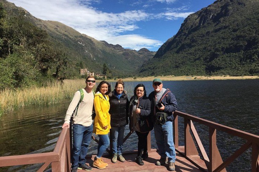 A group of people on a wooden bridge over a lake with mountains in the background. 5