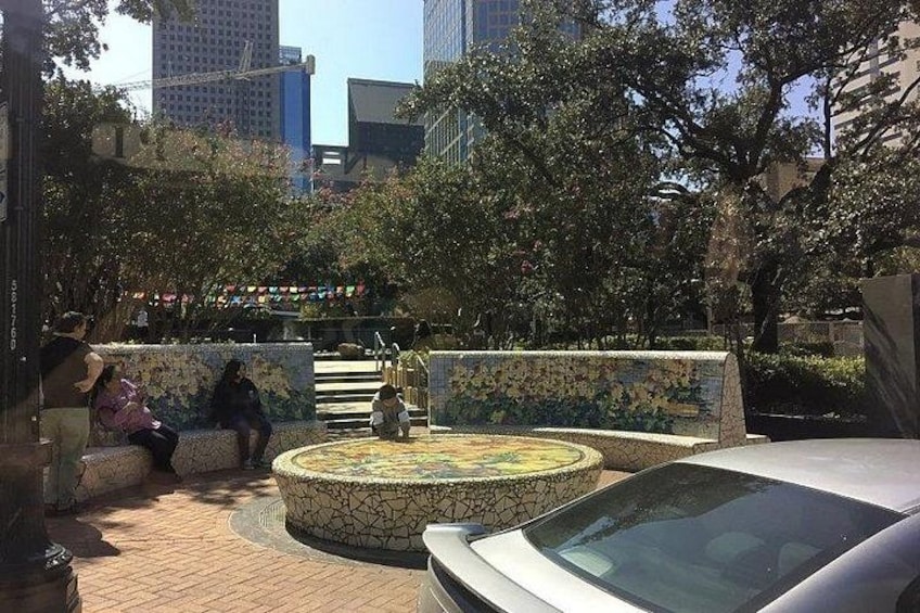 Un patio con una fuente de mosaico, un banco y un coche aparcado cerca. 4