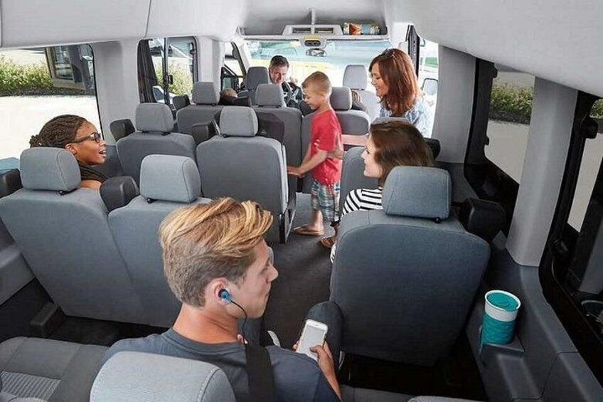 A bus interior with multiple rows of seats and a person holding a phone. 1