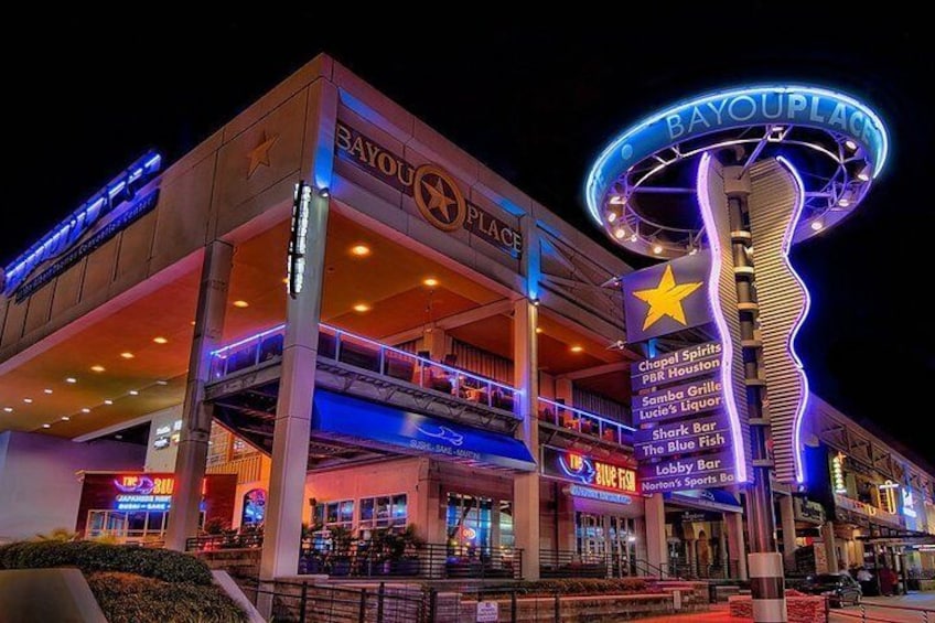 Un centro comercial de varios niveles con un llamativo letrero que dice 'BAYOU PLACE' y una gran estrella iluminada. 2
