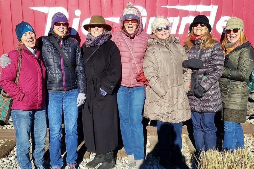 Un groupe de personnes se tient devant un bâtiment rouge, sur lequel on peut apercevoir partiellement le mot « Fierté ». 2