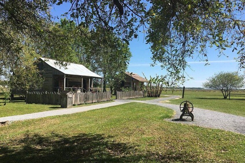 A rustic building with a porch, surrounded by a wooden fence, a gravel path, and a bench. 2