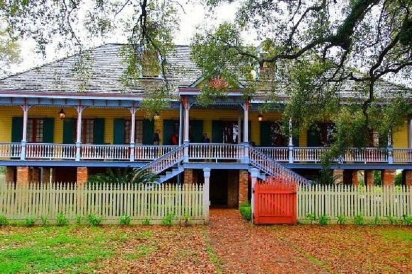 A two-story building with a balcony, a red door, and a white picket fence. 3