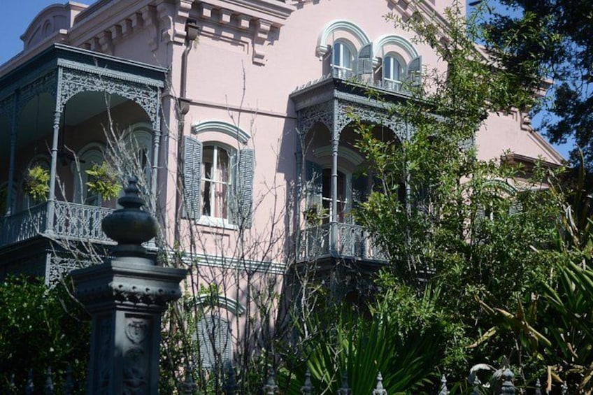 Un edificio rosa con balcones ornamentales y contraventanas verdes. 1
