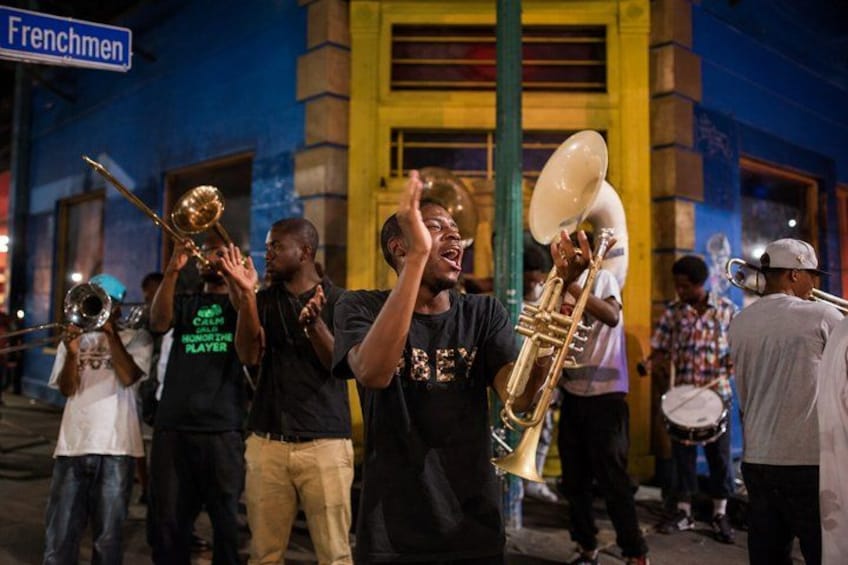 A brass band performing on a street with a building labeled 'Frenchmen' in the background. 2