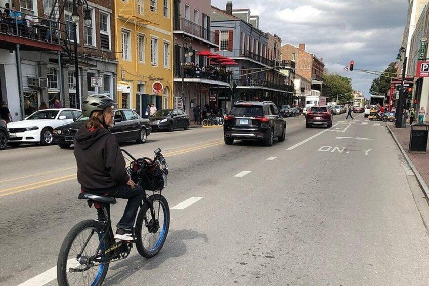 A person riding a bicycle on a city street with cars and buildings. 5