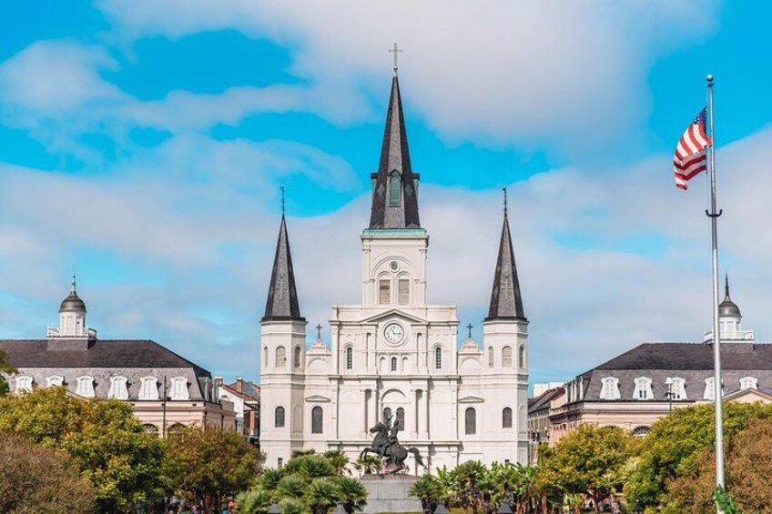 A white church with two spires, a statue in front, and an American flag. 1