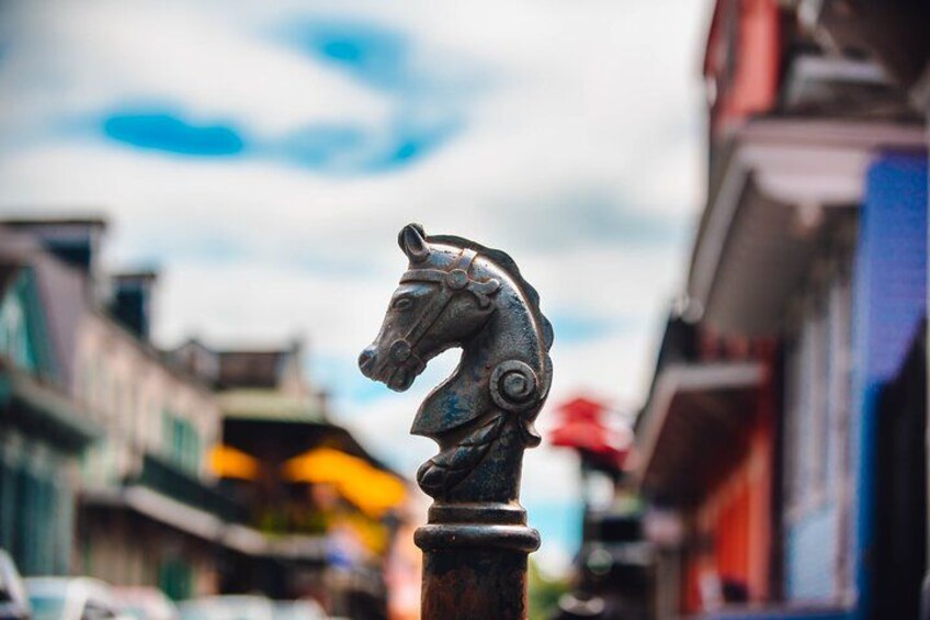 A metal horse head sculpture on a pole, with buildings and a cloudy sky in the background. 4
