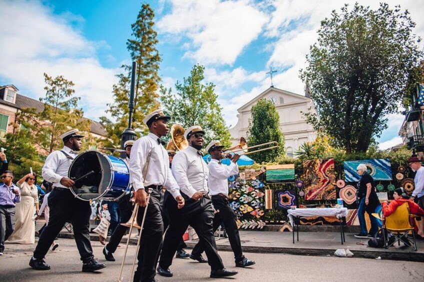 A marching band in uniform, a church, and a crowd of spectators. 3
