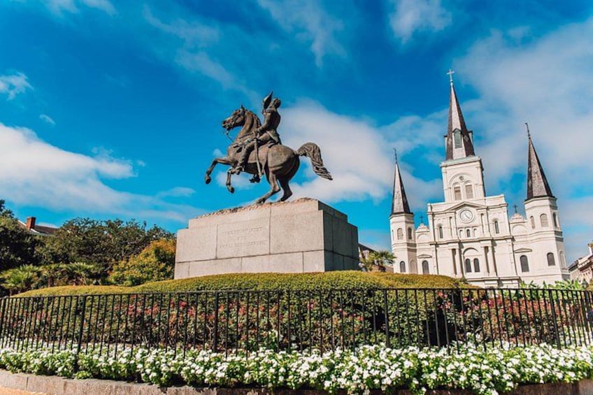 A statue of a person on horseback, a church with multiple spires, and a well-maintained garden with white flowers. 5